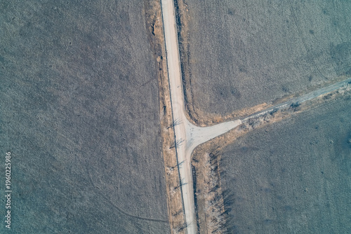 Rural road intersection T-junction in a desolate winter field, transport logistics and terrain mapping, aerial drone perspective