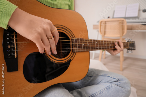 Young girl playing guitar at home, closeup