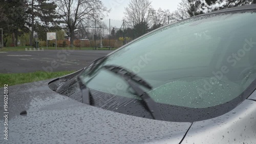Car windshield washer system spraying water on glass during cleaning