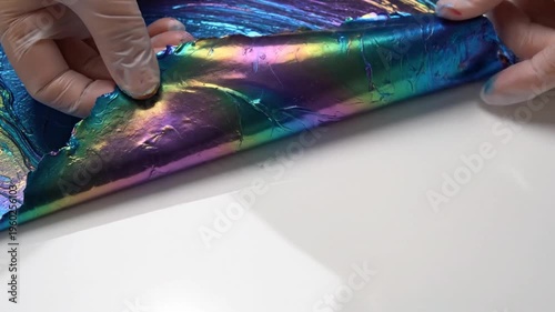 Satisfying iridescent metallic slime being stretched and kneaded by gloved hands