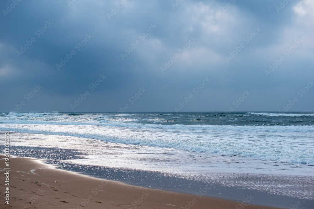 Fototapeta premium Waves and Rocky Cliff Beach in Dramatic Sunlight