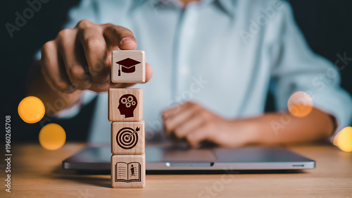 A person arranges wooden blocks with icons representing education goals and strategic thinking high quality