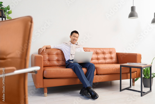 Chinese businessman working with laptop on sofa in office