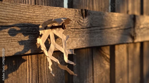 A lone weathered paper bracket hangs from a rusted nail on old wooden boards