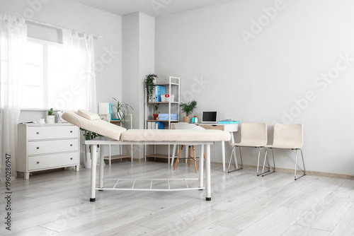 Quadro su tela Interior of medical cabinet with shelving units, couch and laptop on workplace