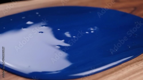 Concentric rings of glossy blue paint forming a ripple pattern on a wooden surface