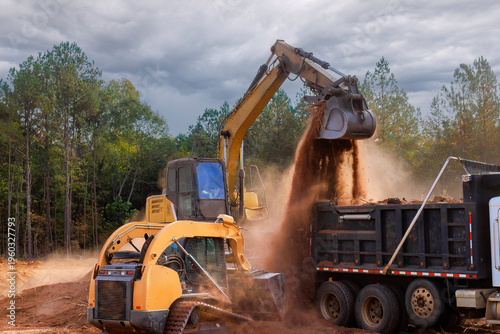 Heavy machinery digs transfers soil to dump truck at construction site at ground leveling