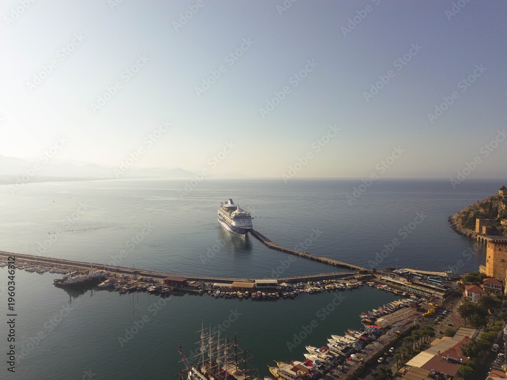 Naklejka premium Aerial drone video of Alanya Harbor in Antalya, Turkey, featuring multiple cruise ships docked at the port.