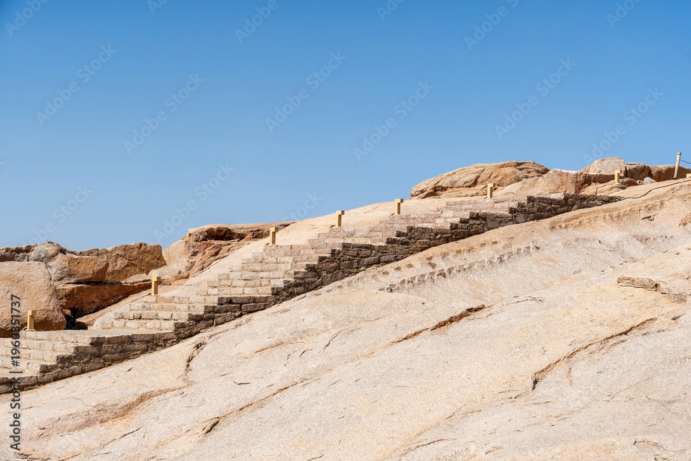 Obraz premium Stone stairs ascend a rugged desert hillside under a clear blue