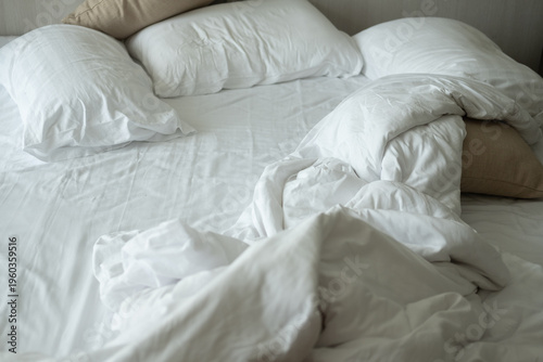 Soft pillows on comfortable bed. Empty bedroom, pillow, blanket and white linen after wake up. The crease of an unmade bed sheet in the bedroom after night sleep and wake up in the morning time.