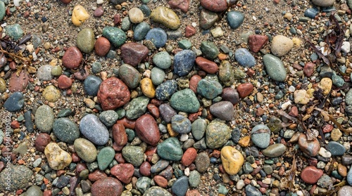 Pebble beach stones in varied colors and shapes, smooth natural ground texture.