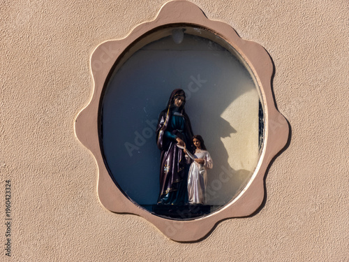 Wallpaper Mural Religious statue of Saint Anne, mother of the Virgin Mary, teaching the child Mary. The figures are displayed inside a star-shaped recessed wall niche on a textured outdoor facade. Torontodigital.ca