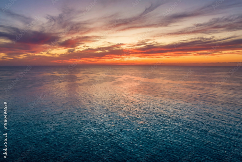 Fototapeta premium Vibrant and colorful sunset over calm ocean horizon