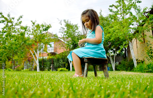 Latin little girl sitting on the stool outdoors.