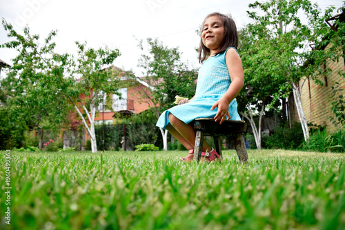 Latin little girl sitting on the stool outdoors.