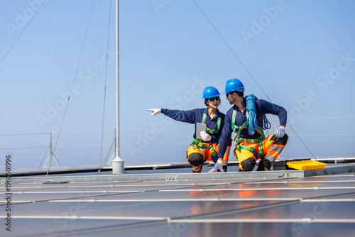 Konstfotografi Team of solar technicians in safety harness discussing installation on rooftop,