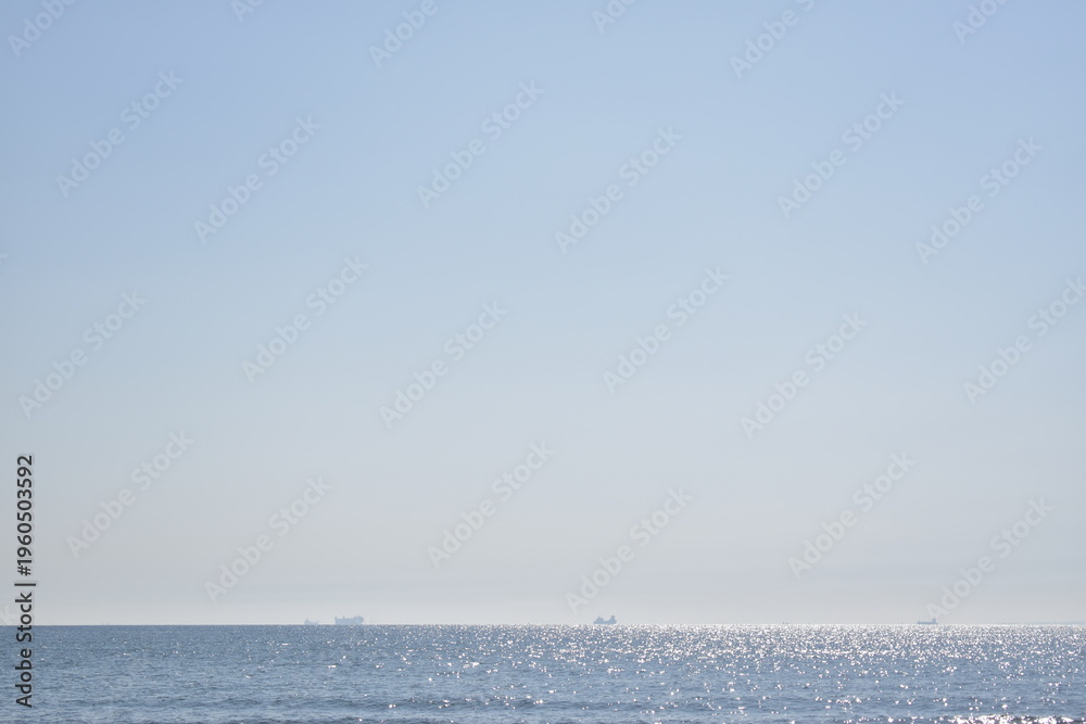 Obraz premium Calm Ocean Horizon with Distant Cargo Ships.