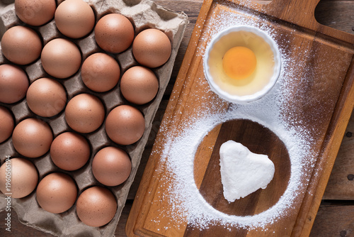Fresh Eggs and White heart-shaped dough Ingredients on Rustic Wooden Table