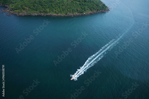 Boat at sea leaving a wake near the island, copy space