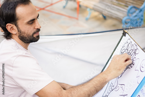 Artist drawing a caricature on a canvas outdoors with charcoal