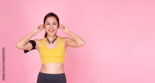 Quadro em tela Happy young Asian woman in sportswear putting on earphones listening to music before workout