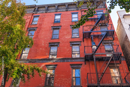 Red brick New York residential building facade with metal fire escape stairs