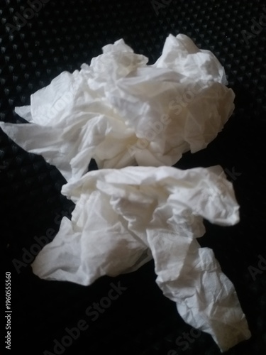 crumpled white tissue paper placed on a dark textured background. Concept of waste, hygiene, cleaning, or environmental pollution. Minimalist composition with strong contrast, 