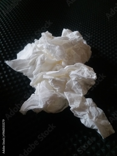 crumpled white tissue paper placed on a dark textured background. Concept of waste, hygiene, cleaning, or environmental pollution. Minimalist composition with strong contrast, 