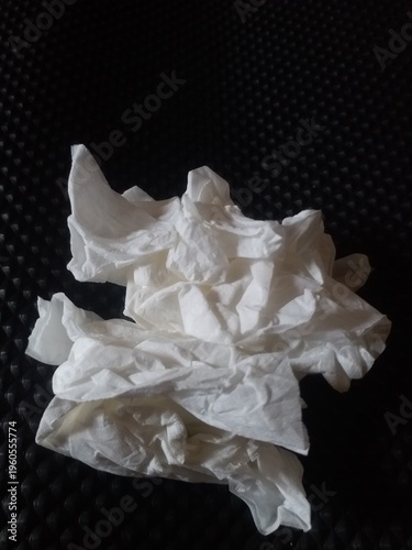 crumpled white tissue paper placed on a dark textured background. Concept of waste, hygiene, cleaning, or environmental pollution. Minimalist composition with strong contrast, 