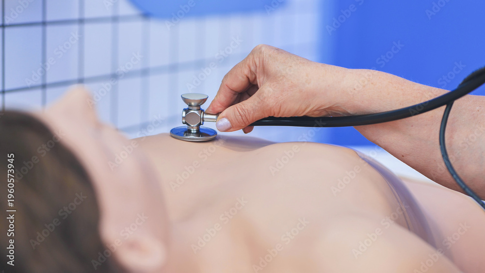 Fototapeta premium Medical professional using stethoscope on training mannequin during clinical simulation course