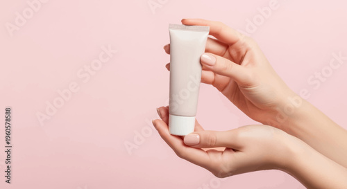Woman's Hands Holding Skincare Cream Tube on Pink Background
