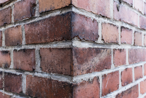 brick wall background, Detailed close-up of a red brick wall corner showing rough mortar joints and weathered surface texture.