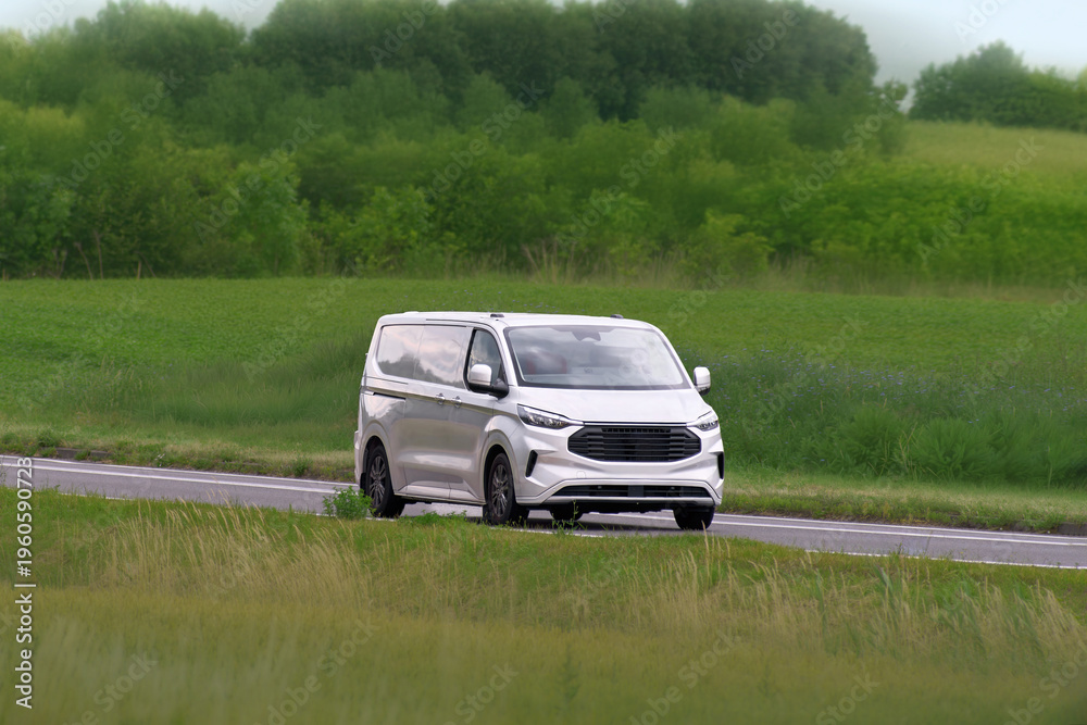 Fototapeta premium Small business delivery van driving in scenic landscape