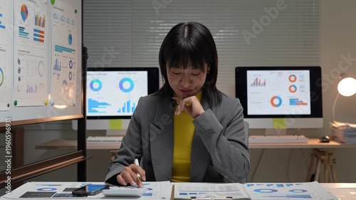 Focused asian accountant working late night at office desk