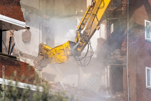 Demolition of brick building with excavator arm