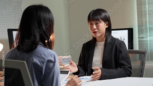 Asian businesswomen discussing project in office at night