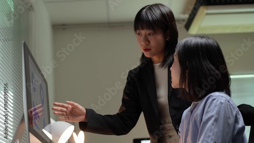 Asian businesswomen collaborating on project at night