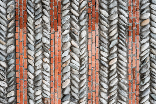 Pebble and red brick paving pattern in a herringbone design, architectural background texture.