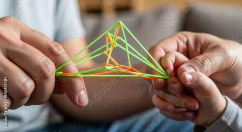 Hands holding geometric rubber band structure.