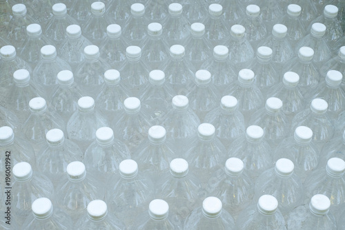 Several empty clear plastic bottles with no caps Several empty clear plastic bottles were stacked in a row.were stacked in a row.