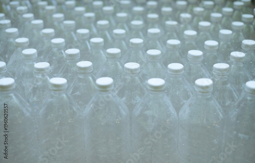 Several empty clear plastic bSeveral empty clear plastic bottles were stacked in a row.ottles with no caps were stacked in a row.