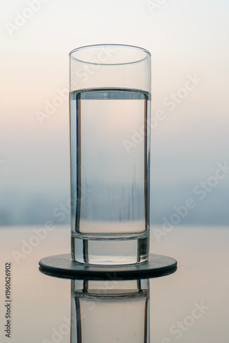 Glass of water on reflective table with city skyline