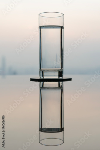 Glass of water on reflective table with city skyline