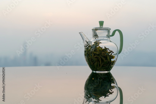 Glass teapot on reflective table with city skyline