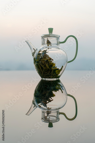 Glass teapot on reflective table with city skyline