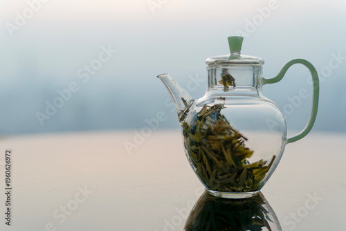 Glass teapot on reflective table with city skyline