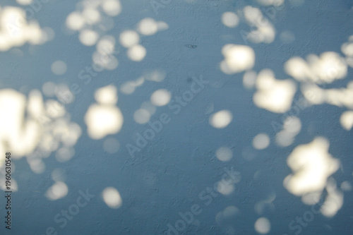 Fotografie Texture background blue grey wall dappled light shadow leaf pattern sun light spots rustic surface