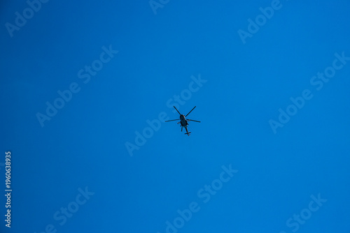 A military helicopter flying against a blue sky