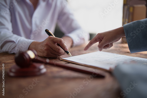 Konstfotografi Client's hand signing a document with a pen during a legal consultation, while a