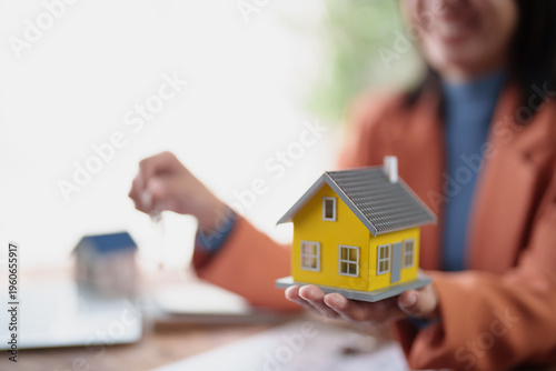 Принти на полотні Real estate agent smiling while presenting a miniature house model and property